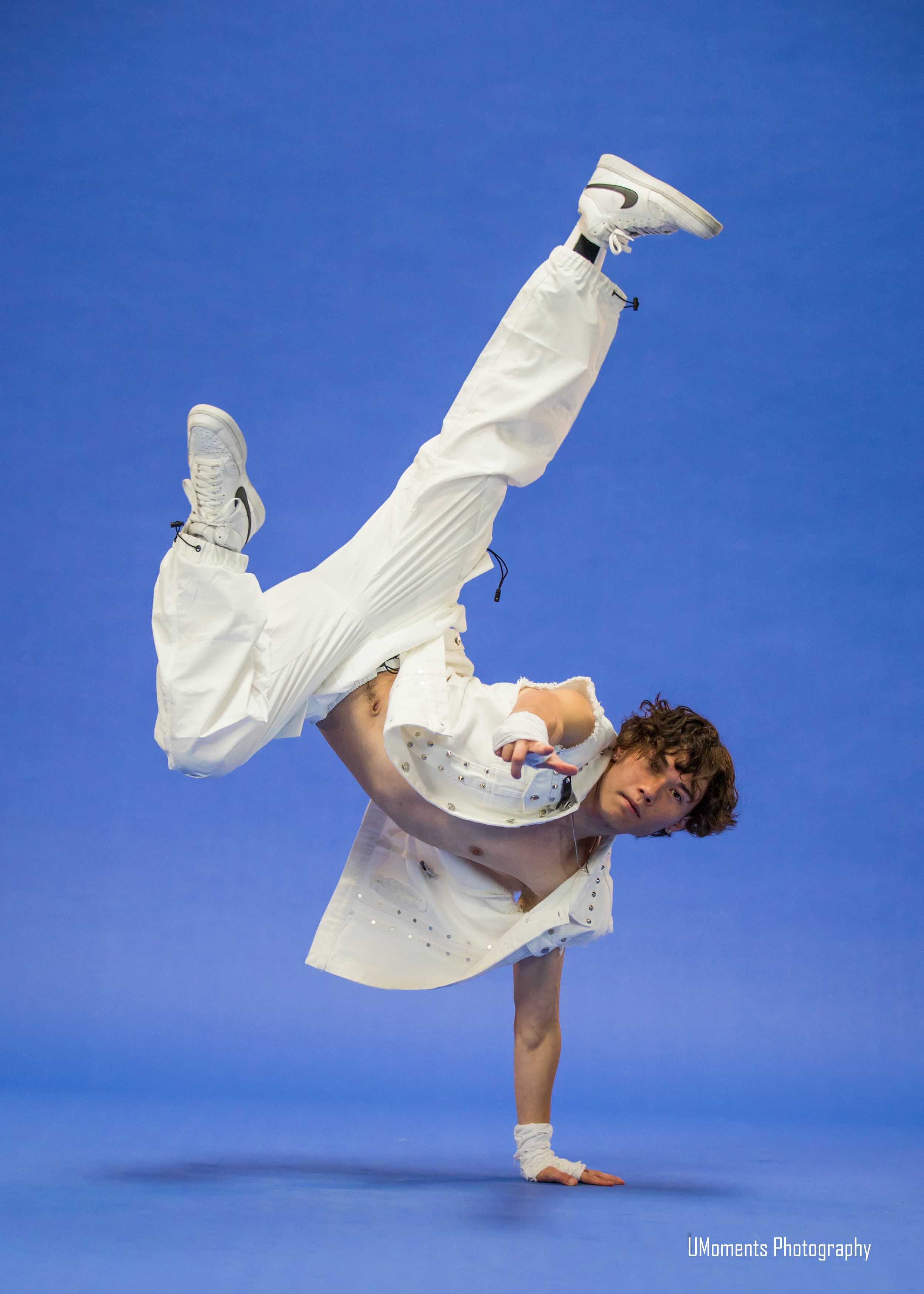 Dancer holding an airborne freeze against a blue studio backdrop