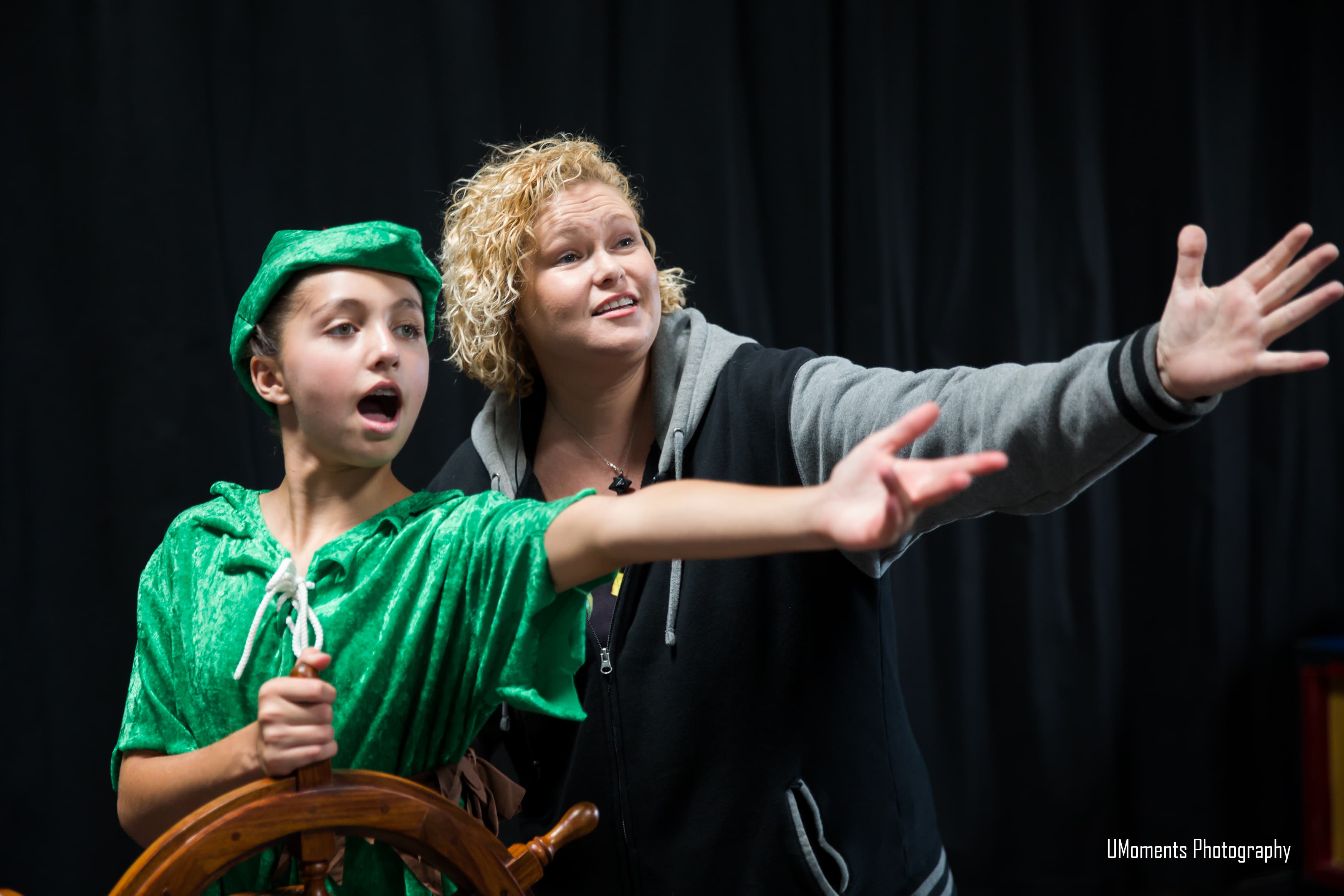 Young performer rehearsing on stage with an instructor