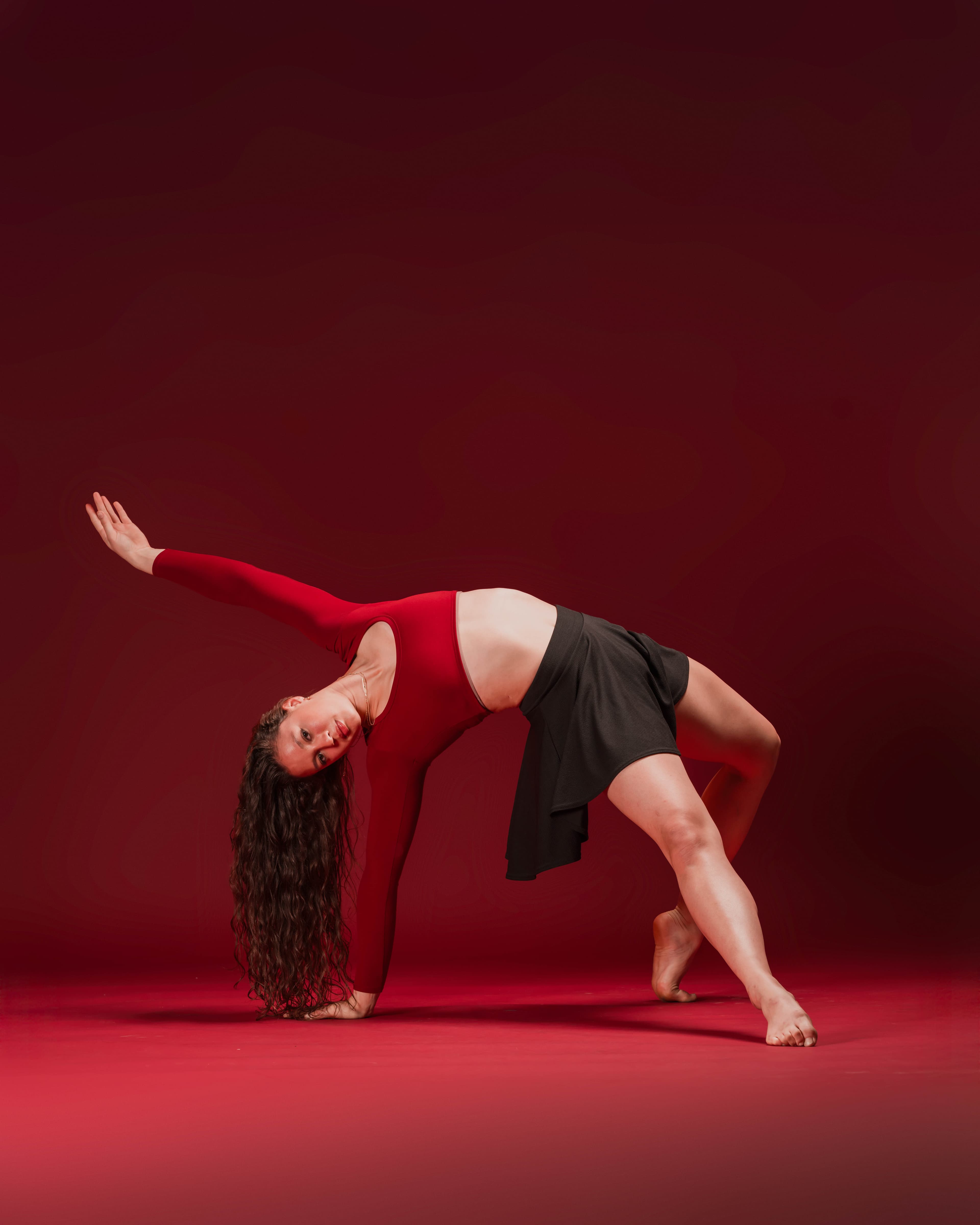 Solo dancer in a red performance costume moving through a backbend
